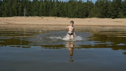 Front view of little boy running into the sea in sunny day, Slow motion Video stock 93389657