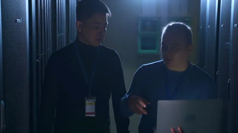 Front view of male engineers talking and working with laptop in render farm Stock Footage 162223907