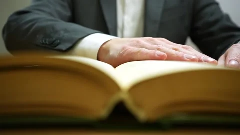 Front view of man in formal suit reading book while sitting at the table 動画素材 236316719