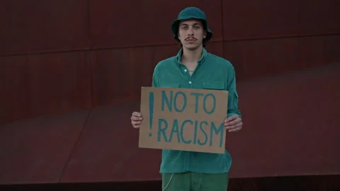 Front view of man holding banner no to racism outdoors Stock Footage 162827950