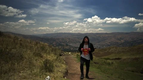 Front view of a man with hood and backpack walking on a trek in a mountain 스톡 동영상 164596828