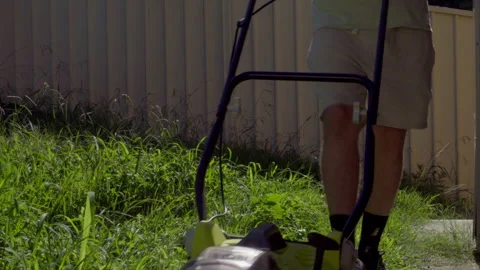 Front View of Man Mowing Overgrown Lawn at Home Stock Footage 329909315