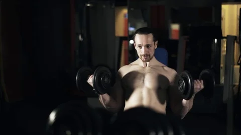 Front view of a man with naked torso doing a dumbbell exercise in gym 스톡 동영상 74278090