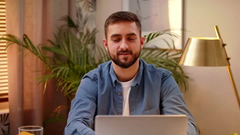 Front View Of Man Sitting In Home Office At Desk Working on Laptop Stock Footage 147004383