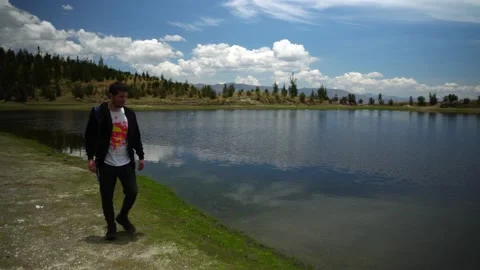 Front view of a man walking and looking at the Radian lagoon that filters water Stock Footage 164597840