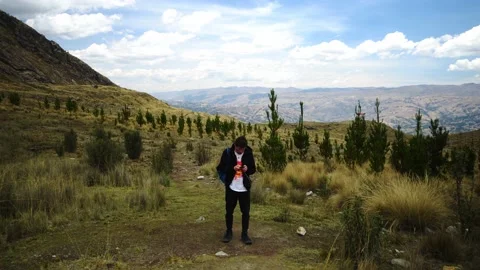Front view of a man walking on a trek through the mountains among bushes and 스톡 동영상 164597142