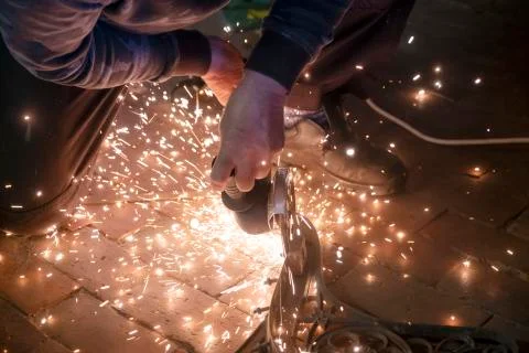 Front view of a man's hands working on a metal part of a garden bench, using  Foto stock
