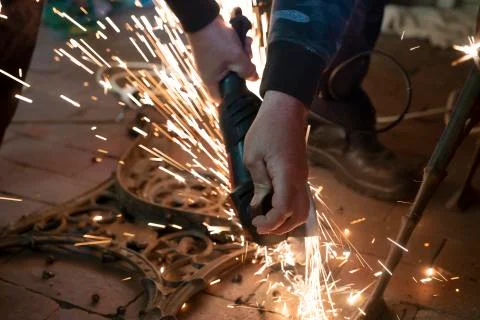 Front view of a man's hands working on a metal part of a garden bench, using  Stock Photos