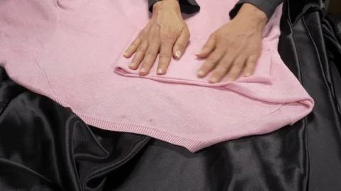 Front view-merchandiser folding a pink luxury Men Casual Classic Sweater 4k. Stock Footage 96291738