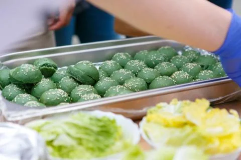 A front view of metal container with green coloured buns for mini hamburger Stock Photos
