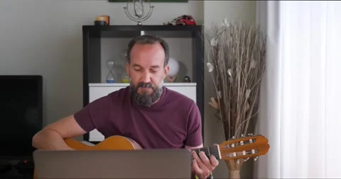 Front view of middle-aged man at home playing guitar with the help of his lap Stock Footage 155276691