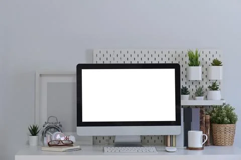 Front view mock up computer with blank screen, books and houseplant on white Foto stock