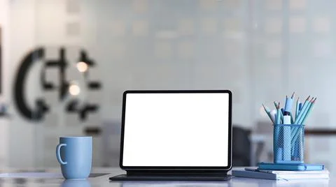 Front view of mock up tablet computer, coffee cup, notebook and stationery on Stock Photos