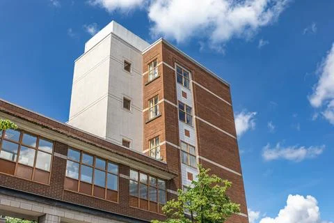 Front view of modern red brick building facade against blue sky. Stock Photos