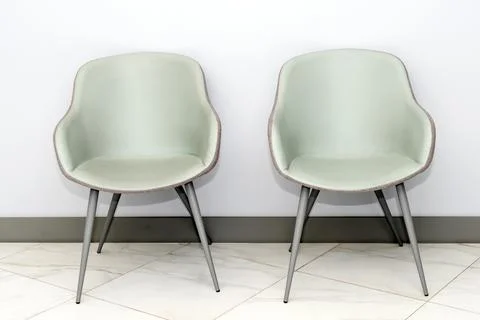 Front view of modern, simple chairs against grey wall in a minimal style, wai Stock Photos