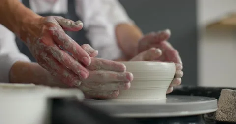 Front view of mother and son hands making ceramic pot on pottery wheel. Hands of Stock Footage 155758597
