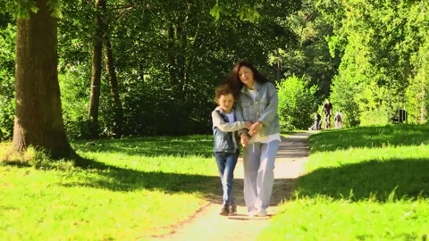 Front view of mother walking down the street with son on sunny day in public Stock Footage 319765795