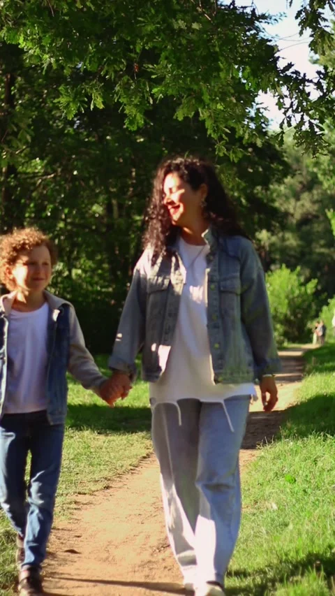 Front view of mother walking down the street with son on sunny day in public Stock Footage 320252635