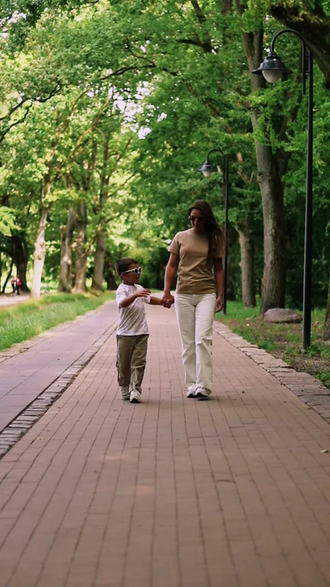 Front view of mother walking down the street with little son with sunglasses Stock Footage 321897703