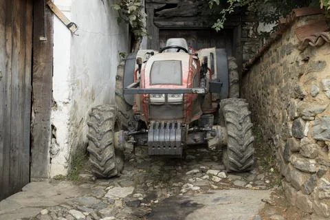 Front view of muddy compact tractor in alley Stock Photos