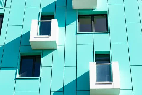 Front view of a multi-storey green modern building with small balconies Stock Photos