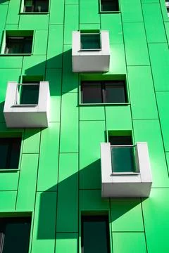 Front view of a multi-storey green modern building with small balconies Stock Photos