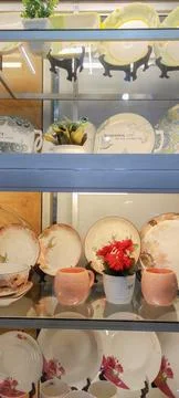 Front view of multiple ceramic plates and mug on displays in dishware store. Photos