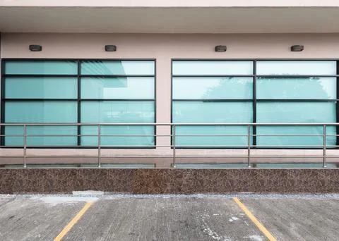 Front view of an office building with square glass windows and ground parking Stock Photos