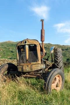 Front view of an old abandoned rusty agricultural tractor in a grass field Stock Photos