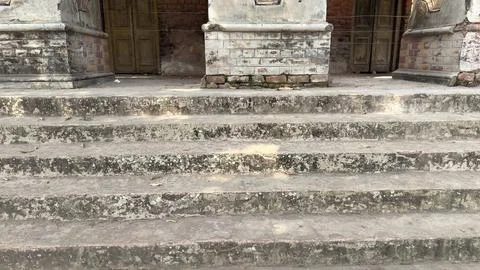 Front view of old, worn stone steps showing signs of age and neglect, with gr 库存照片