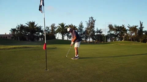 Front view of an older man performing a golf ball shot into the hole. He dr.. Stock Footage 252603856