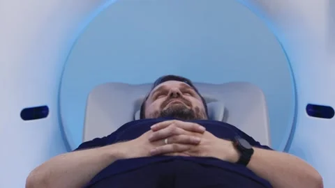 Front view of patient lying in MRI machine with hands folded Stock Footage 335523465