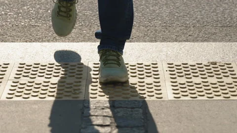 Front view pedestrian feet stepping on tactile warning paving at urban crosswalk Stock-Footage 344187766