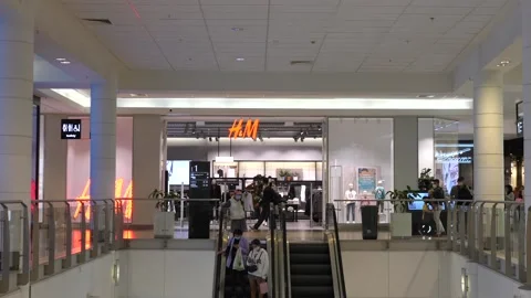 Front view of people on moving stairs all in protective face masks next to H&amp;M Stock Footage 141681811