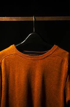 Front View of Plain Orange Sweatshirt on Hanger, Isolated on Black Background Stock Photos
