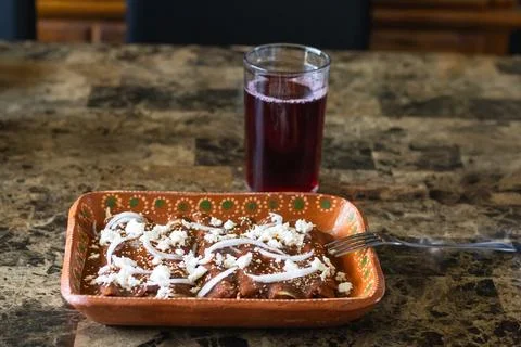 Front view of plate with enchiladas with red mole sauce with onion and chee.. Photos