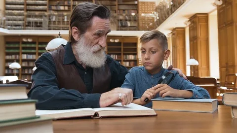 Front view of pleasant bearded man which explaining to his teen grandson the Video stock 119761012