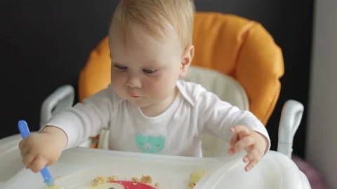 Front view. Portrait. Little boy eats baby food in a feeding chair. Stock Footage 133439495