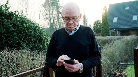 Front view portrait of senior man using his smart phone while he stands outside Video stock 104608849