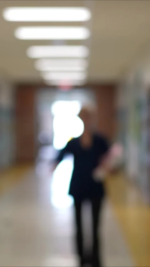 Front view portrait of teacher walking into focus in hallway and smiling in an Stock Footage 295072903
