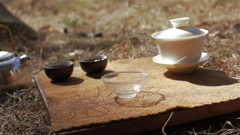 Front view pouring water into shining tea bowl cup over forest background.  動画素材 120060170