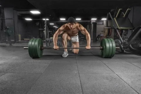 Front view of power athletic guy standing with barbell workout in the gym 스톡 사진