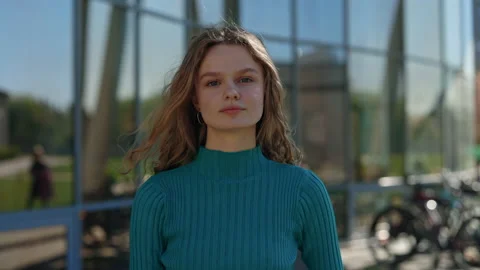 Front view of pretty young lady with blue eyes standing outdoors looking at Stock Footage 162659141