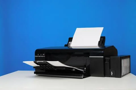 Front view of a printer and a blank sheet of A4 paper on a blue background. Stock Photos