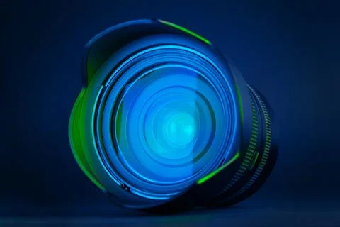 Front view of professional camera lens glowing with blue and green light on.. Stock Photos