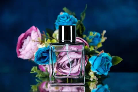 Front view of rectangle perfume bottle colored flowers isolated on dark blu.. Stock Photos