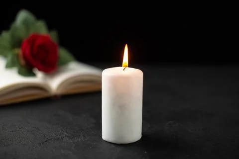 Front view of red rose with open book and candle on the dark background war.. Stock Photos