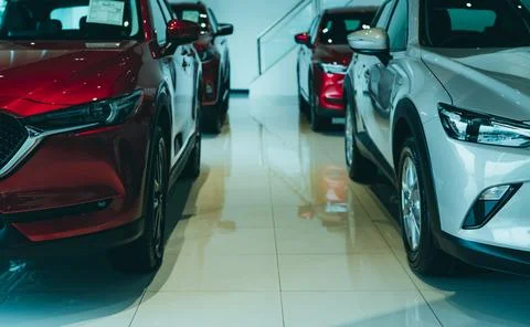 Front view red SUV and white car parked in luxury showroom. Car dealership of Stock-Fotos