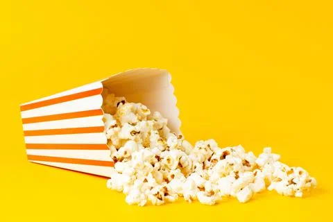 A front view slated popcorn inside package spread all over the yellow backg.. Stock Photos