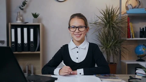Front view of smiling happy likable schoolgirl in uniform which sitting over her Stock Footage 124698128